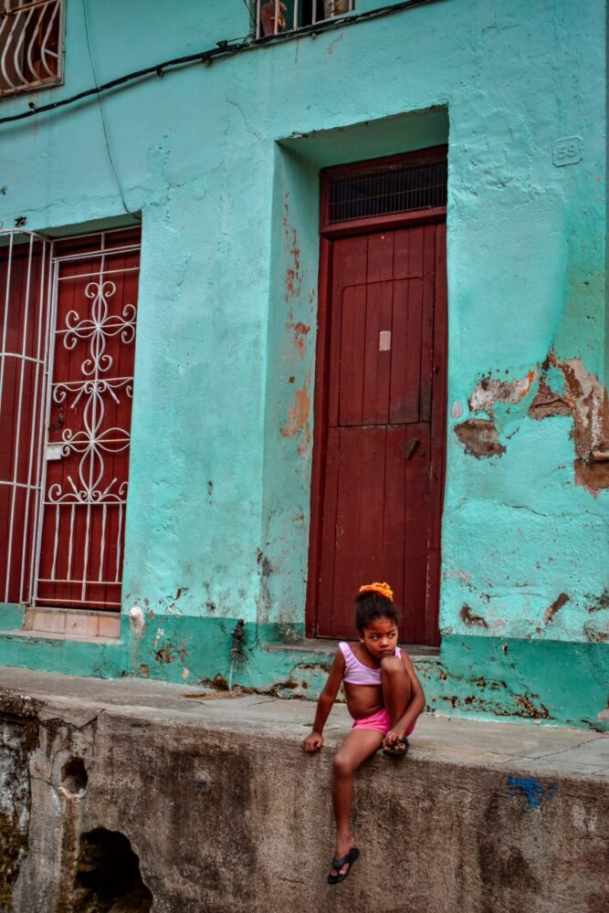 Small child sitting on a sidewalk in cuba  