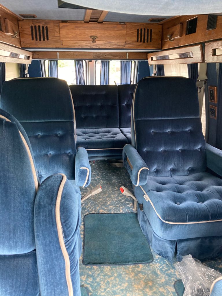The interior of an old 1990s van with massive velvet royal blue chairs inside. Things we love about our campervan