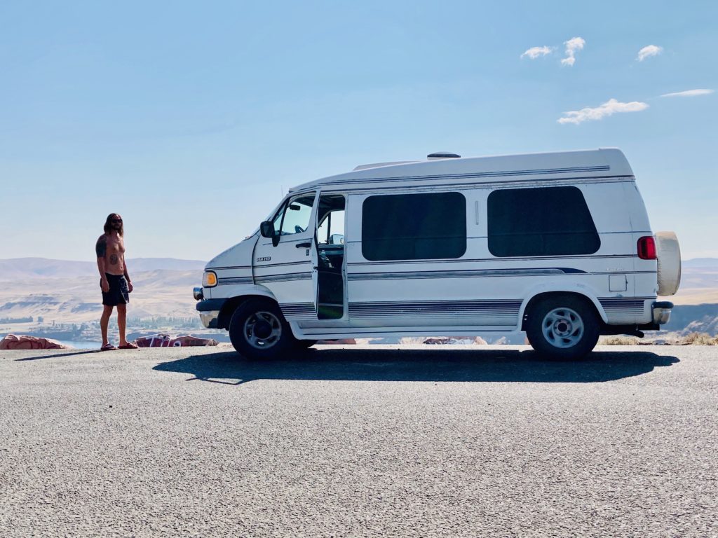 white van parked along canyon with man shirtless. 