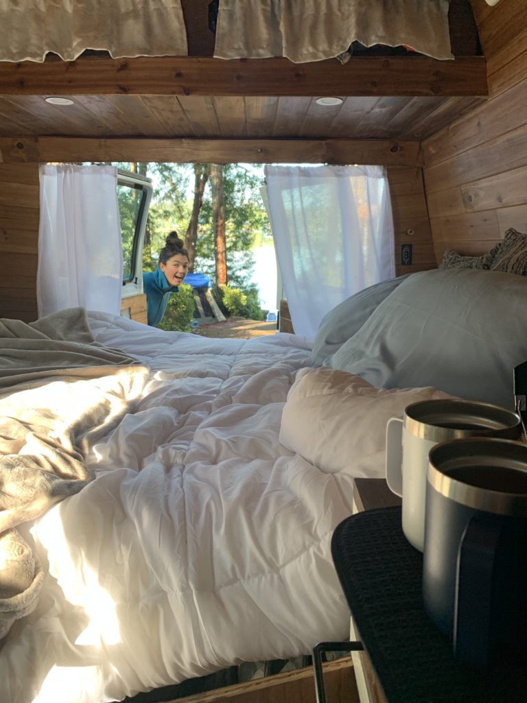 Stealth camping. Coffee cups by white bed inside van. 