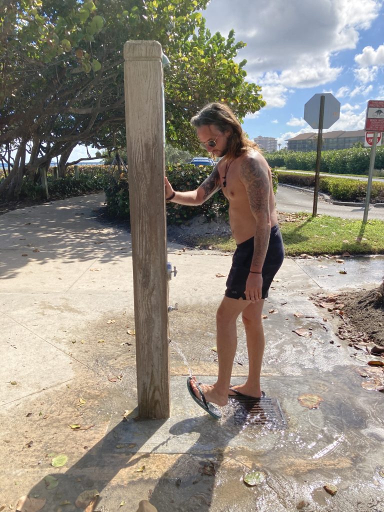 Van life tips for Florida. Man using beach shower. 