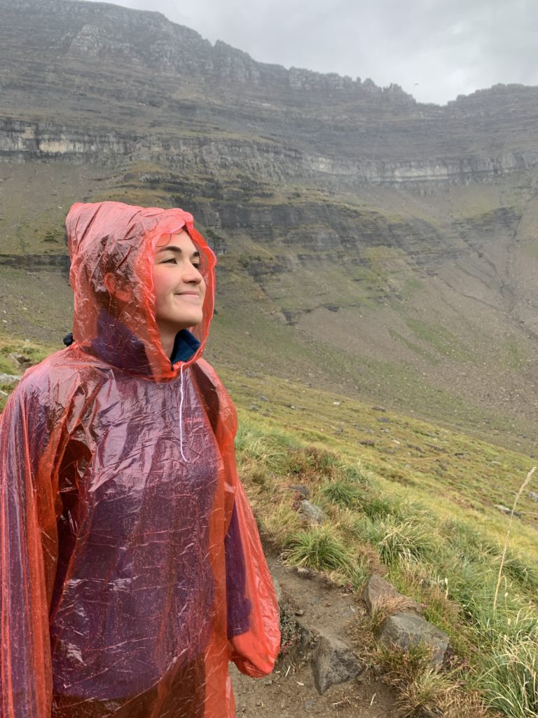 raining, standing in red poncho on hike. 