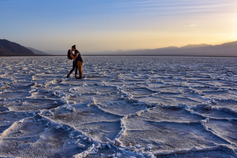 Couple kissing in a sunset over the white flats of bad water basin in Death Valley. Van life with your partner