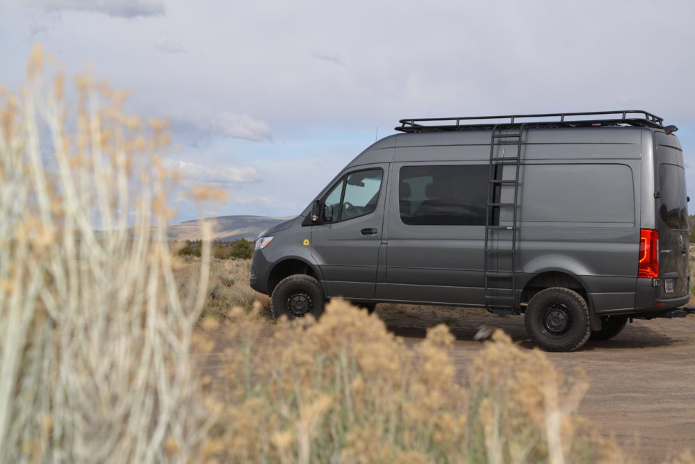 dark grey sprinter van sitting in yellow grassy field. 