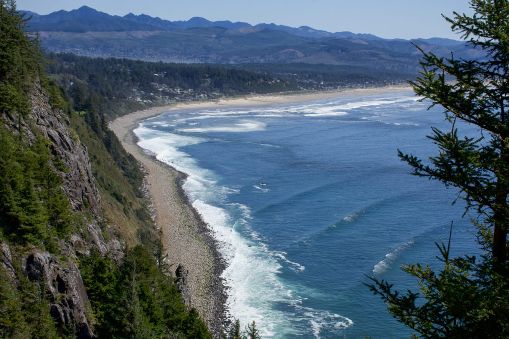 View from above of rugged cliffside coastline and bright blue ocean water. 