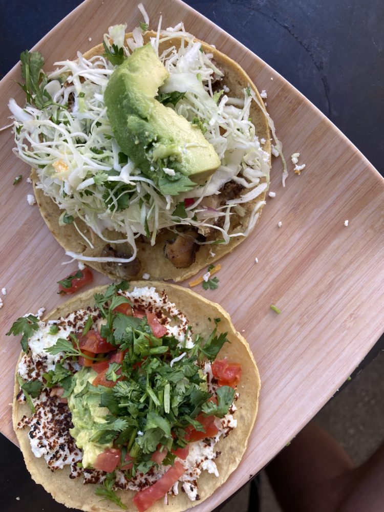 two fully topped tacos on a table. 