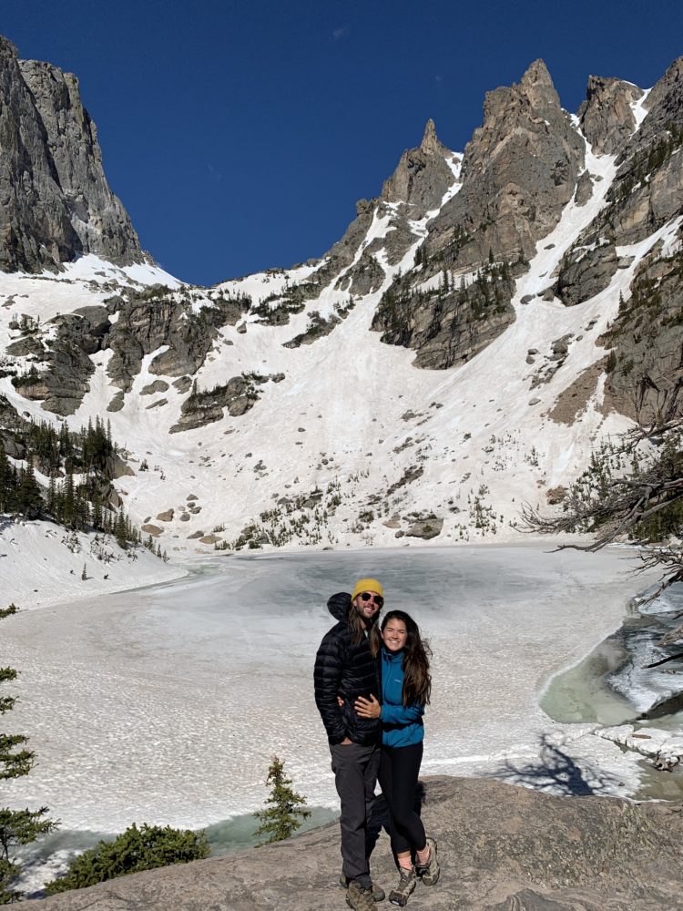 couple standing in front of a snow covered mountain in rocky mountain national park 