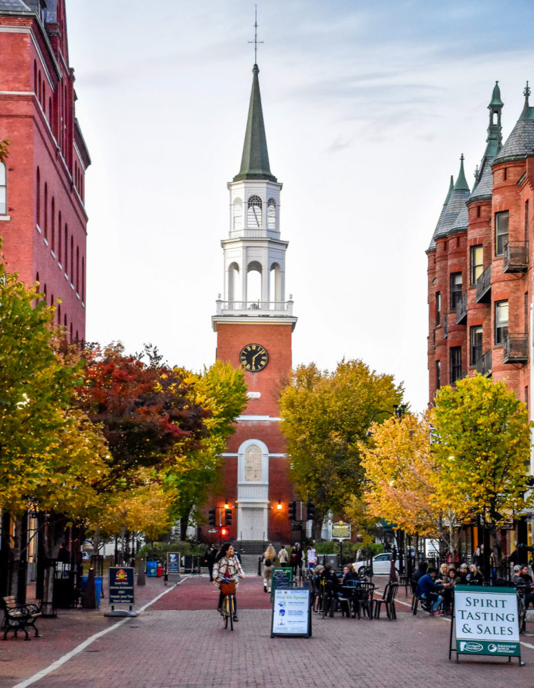 Church street marketplace in Burlington, VT. A massive white steepled church at the head of an all brick town center. 