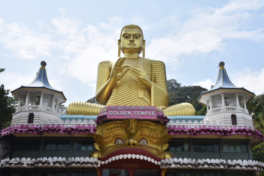 large gold buddha over a temple 