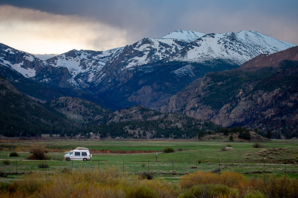 white van at Rocky Mountain National Park with the snow capped mountains in the background 