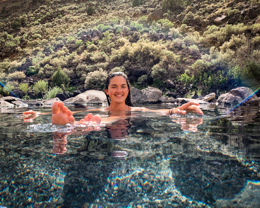 woman soaking in a clear water pool that is a natural hot spring. Guide to New Mexico. 
