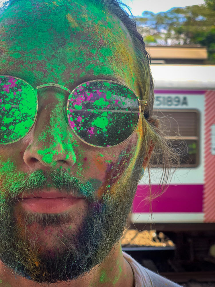 man with multi-colored face paint on holi in India 