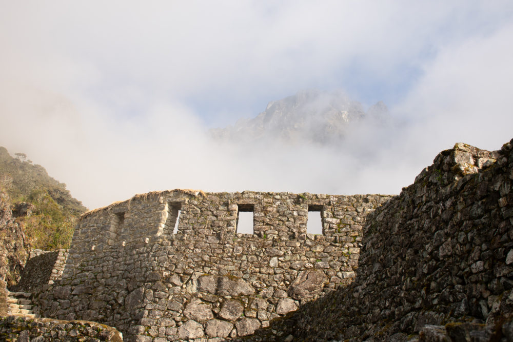 Inca site with a fogged in mountain behind it. 