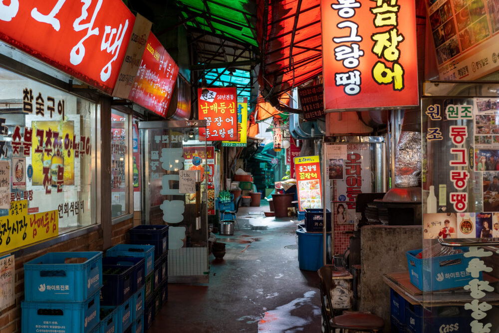 A narrow alleyway covered in signs in South Korean. 