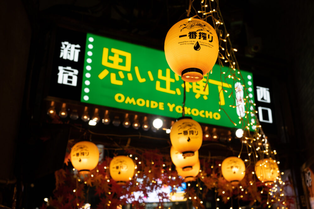 Yellow lanterns and green sign for "Omoide Yokocho" otherwise known as drinking street or piss alley. 