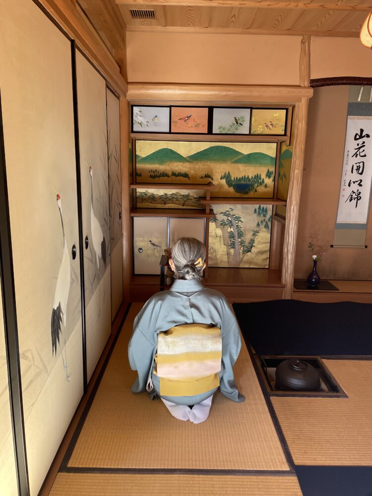 woman sitting in a kimono for a tea ceremony indoors. 