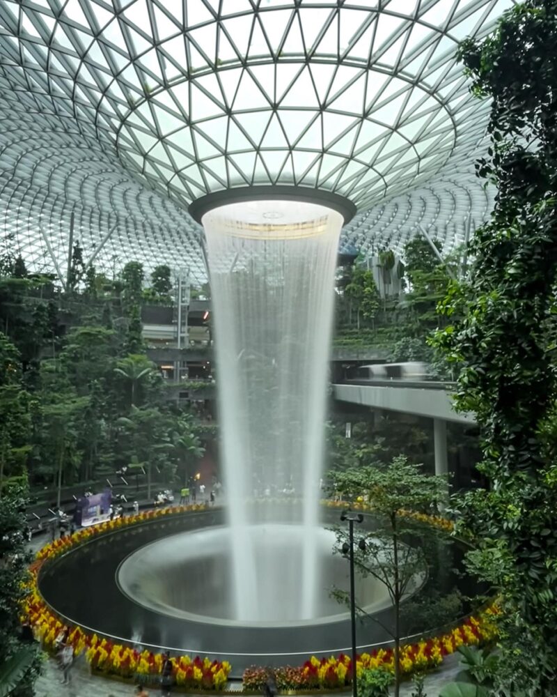 Giant indoor waterfall surrounded by green plants and nature inside the Singapore airport