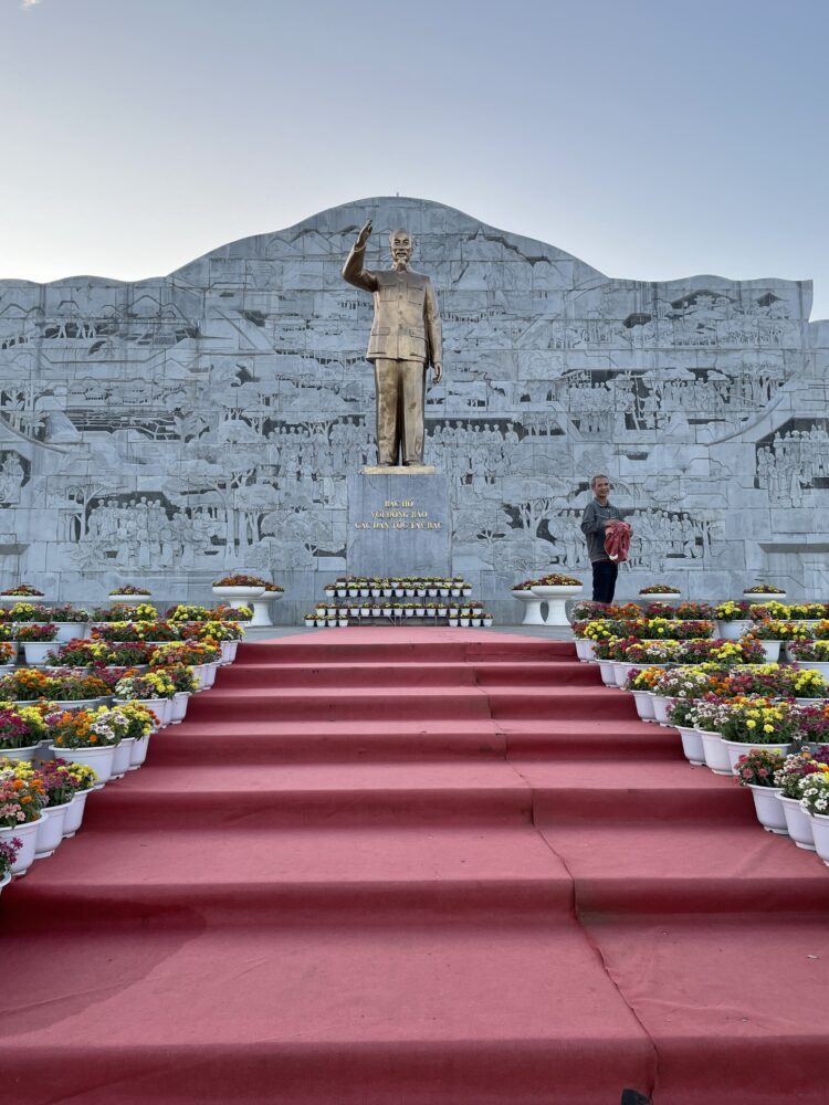 Statue of Ho Chi Minh by a red carpet and lots of flowers