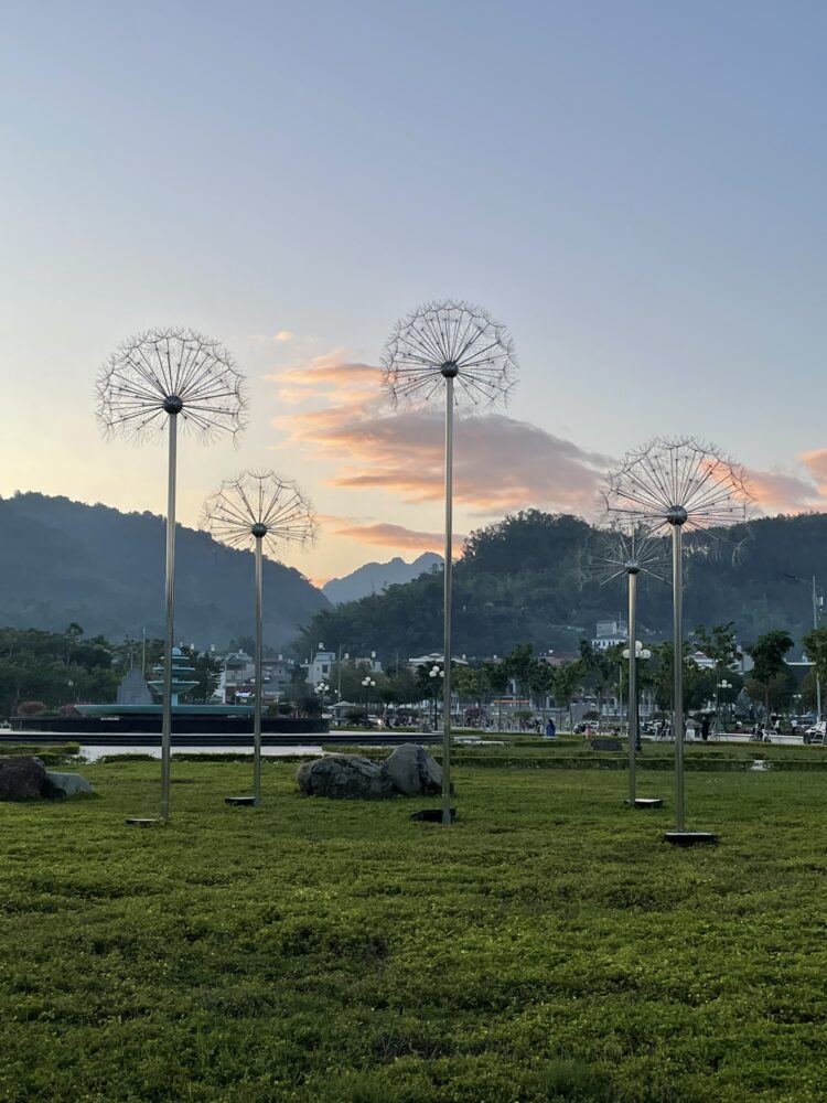 Sunset with some dandelion statues in a green park. 