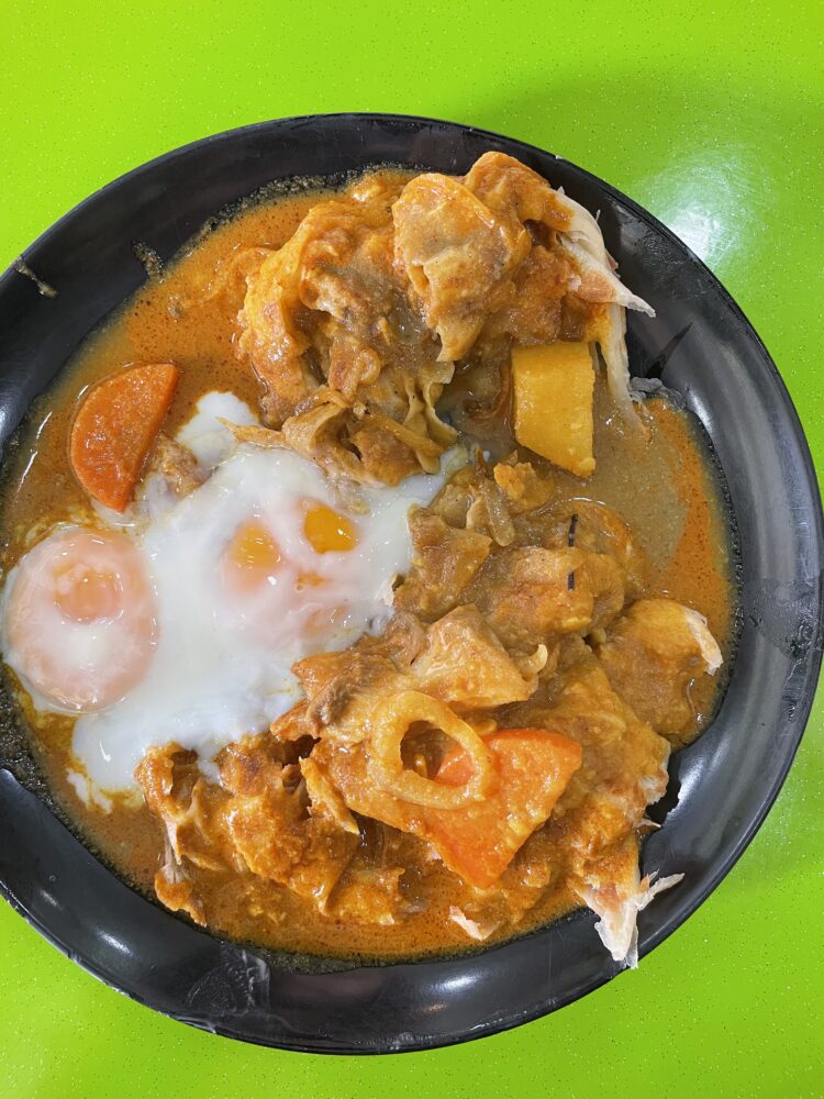 Plate of egg curry and roti on a green table 