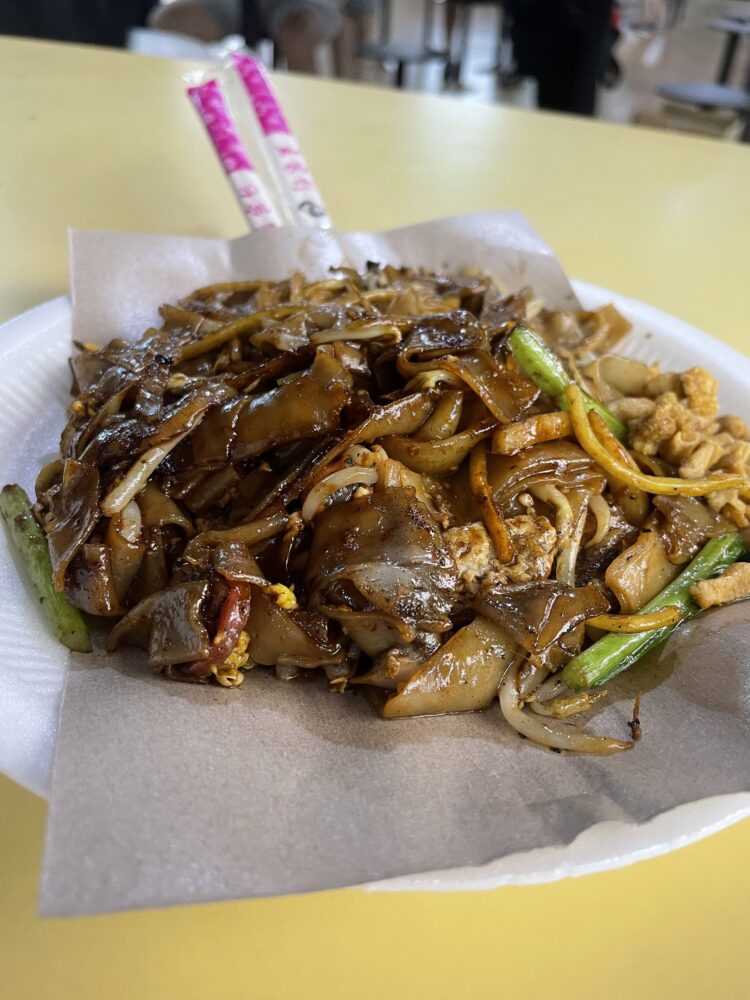 a delicious pile of black sauce covered noodles and vegetables. 