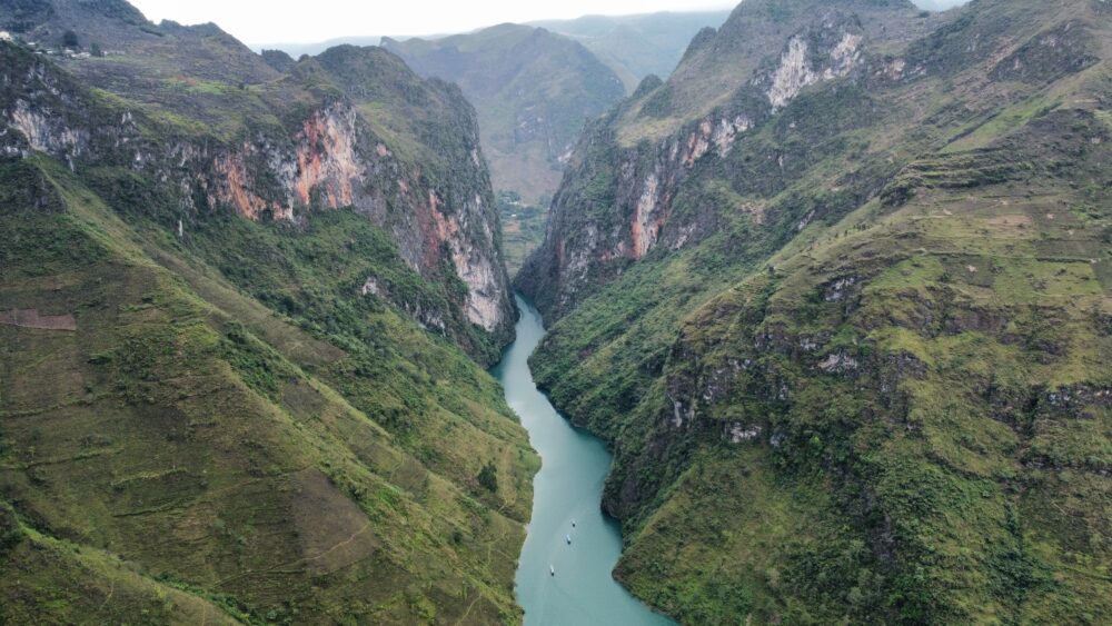 View of the blue river from above with the green canyons around it. 