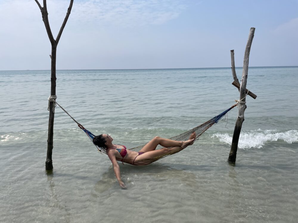 Woman floating in a sea hammock with waves. 