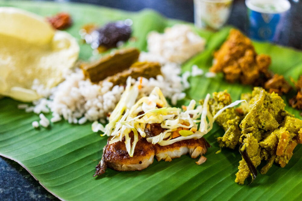 A bunch of curries on a green banana leaf on a street food tour in Mumbai 