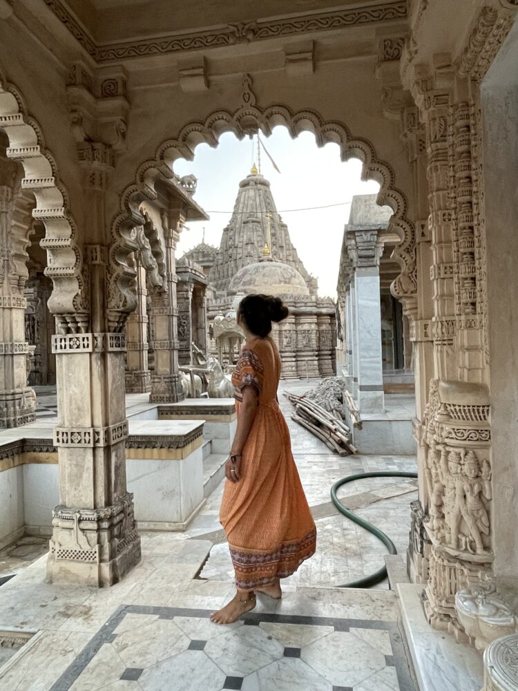 Woman standing in front of intricately carved temples in my palitana guide. 