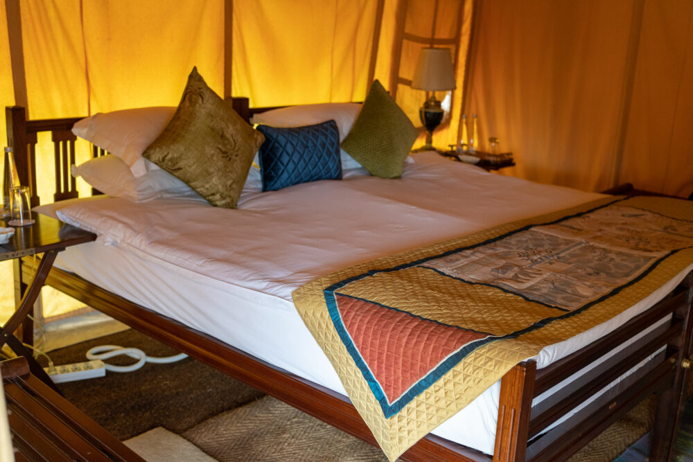 A bed with peacock like colors inside the glamping tents of Dera Amer Wilderness Camp
