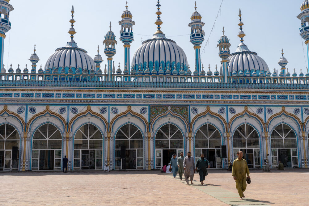 Blue mosque in Islamabad with men leaving the prayer room inside 