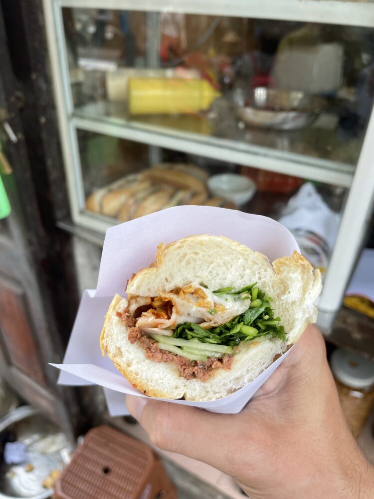 a bahn mi sandwich held in one hand. 