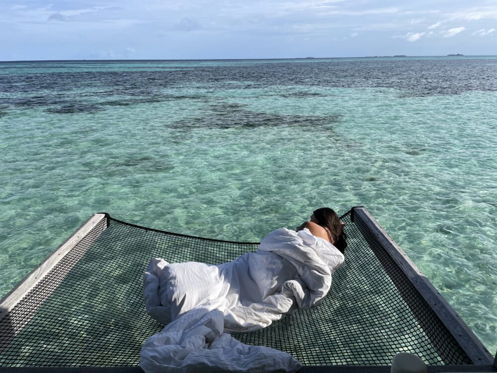 woman wrapped in a blanket on a net over the water 