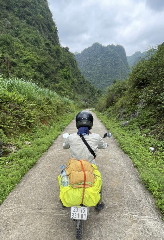 Man on a motorcycle on a small path surrounded by lush jungle 