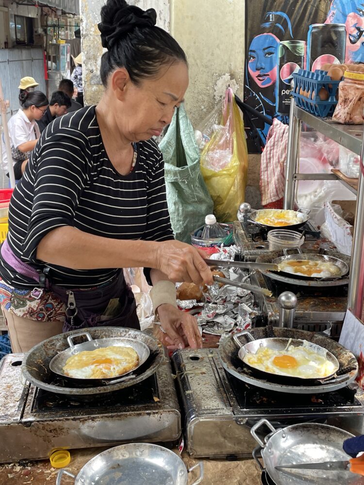 a woman cooking eggs on the street in district 3 HCMC 