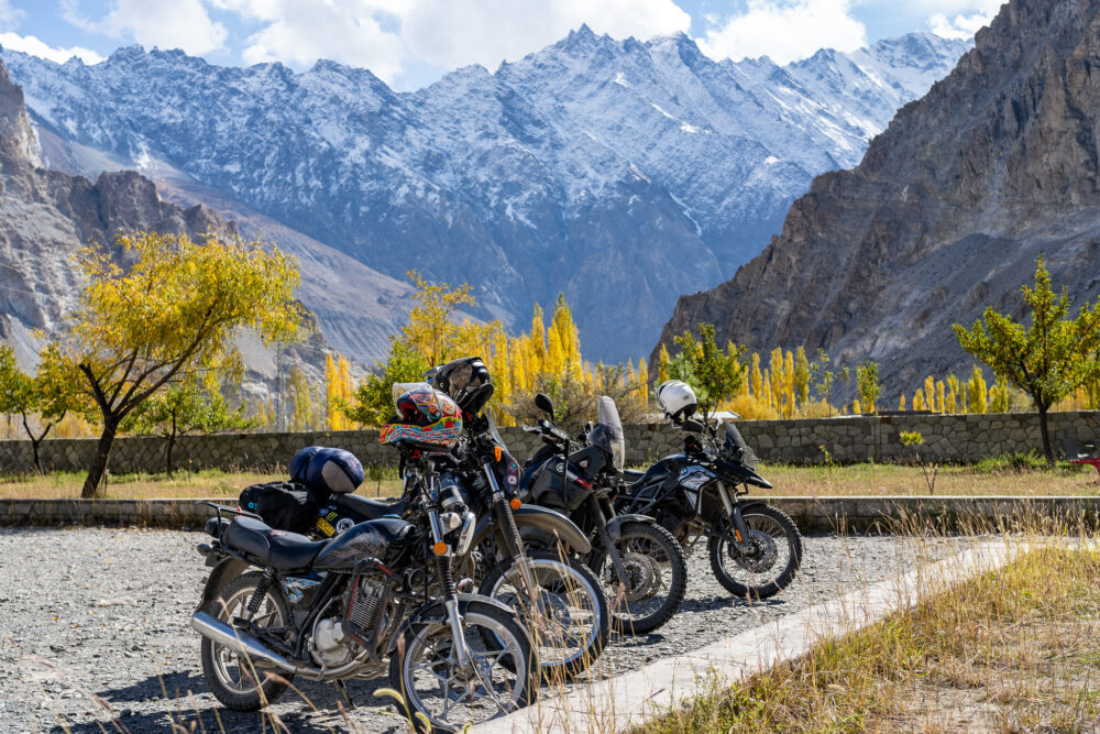 Motorcycles parked outside in Passu with lots of fall colors on the trees and foliage 