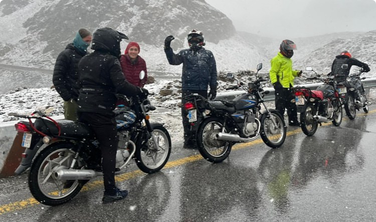 Bikers on the road in a blizzard looking very cold. 