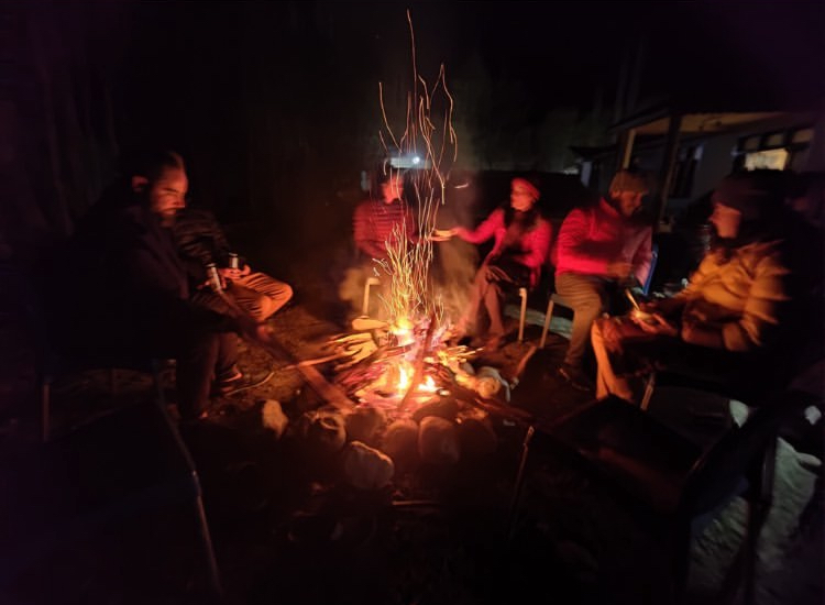 A group of people huddled around a bonfire late at night. 