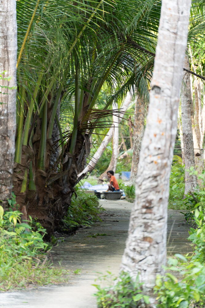woman washing the dishes on a pathway in the jungle 