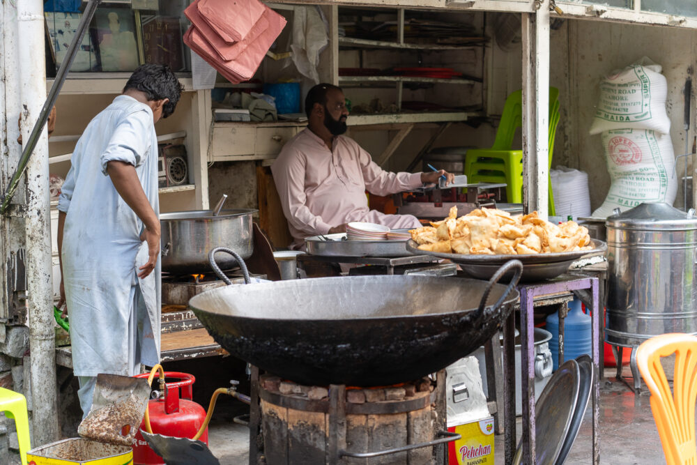 Pakistani man making street food in a giant wok. 