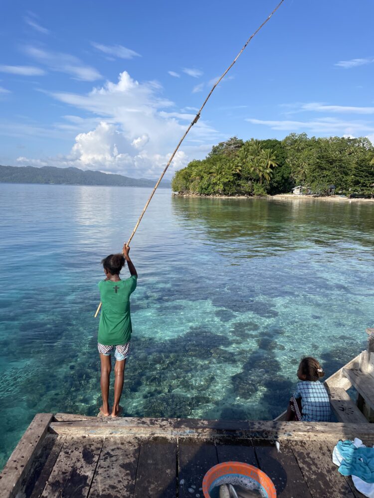 Girl fishing with a wooden pole off the dock in Friwen island 