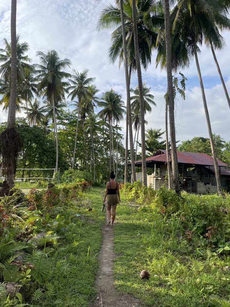Woman walking down a small path surrounded by palm trees 
