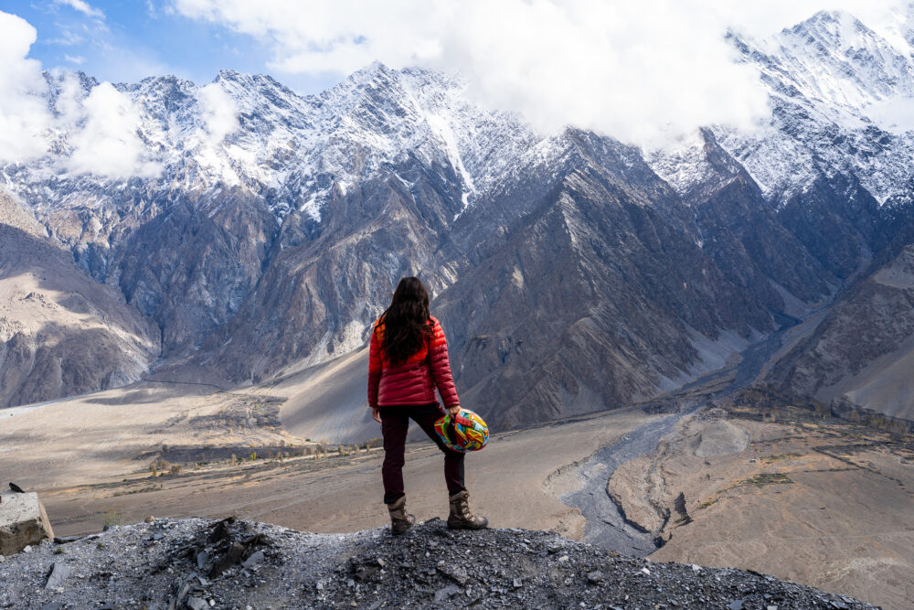 A woman stands by an impressive view of the Passu cones. 