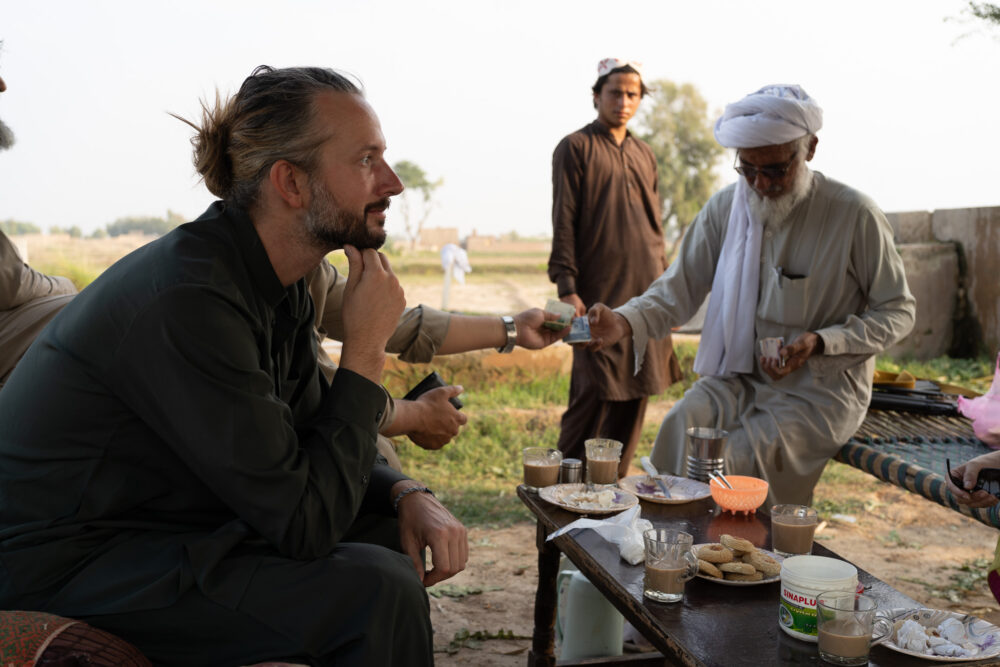 us sharing tea and cookies with a group of pakistani men in a field
