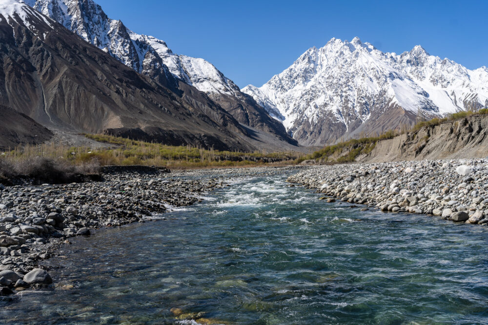 A flowing river with mountains behind it. 