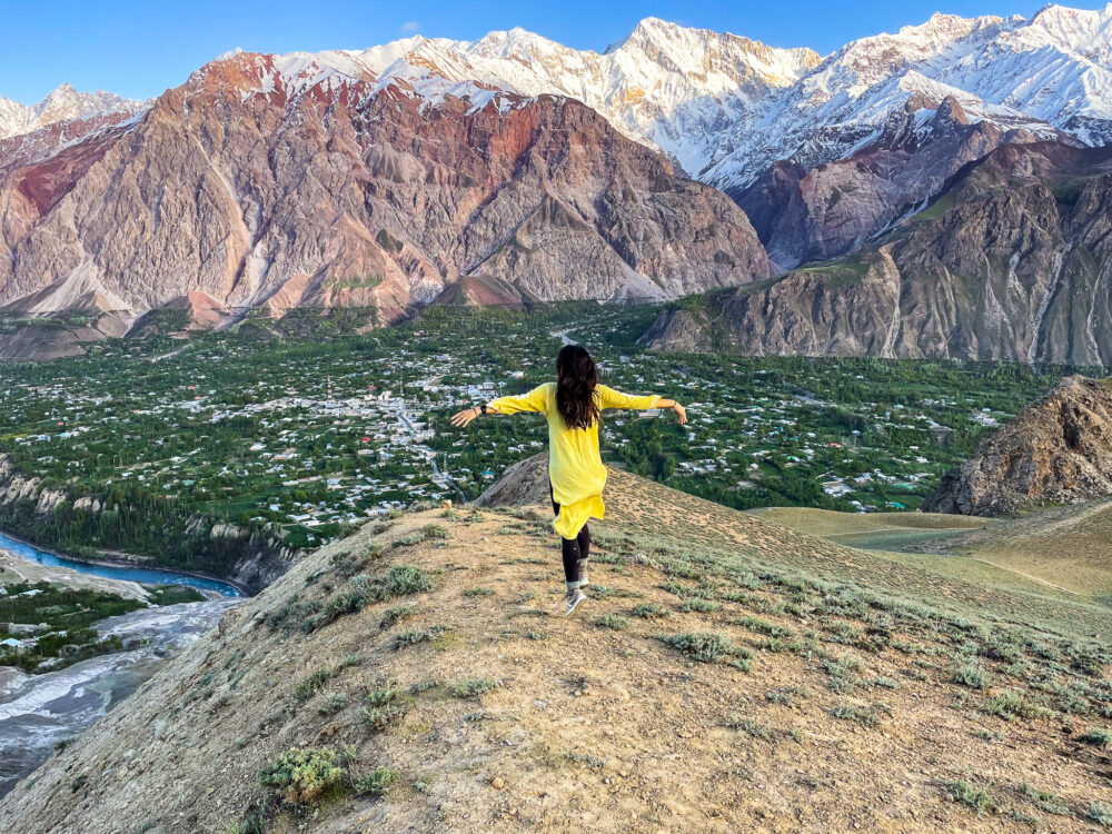 Woman frolicking on the top of a valley looking out at some snowy mountains 