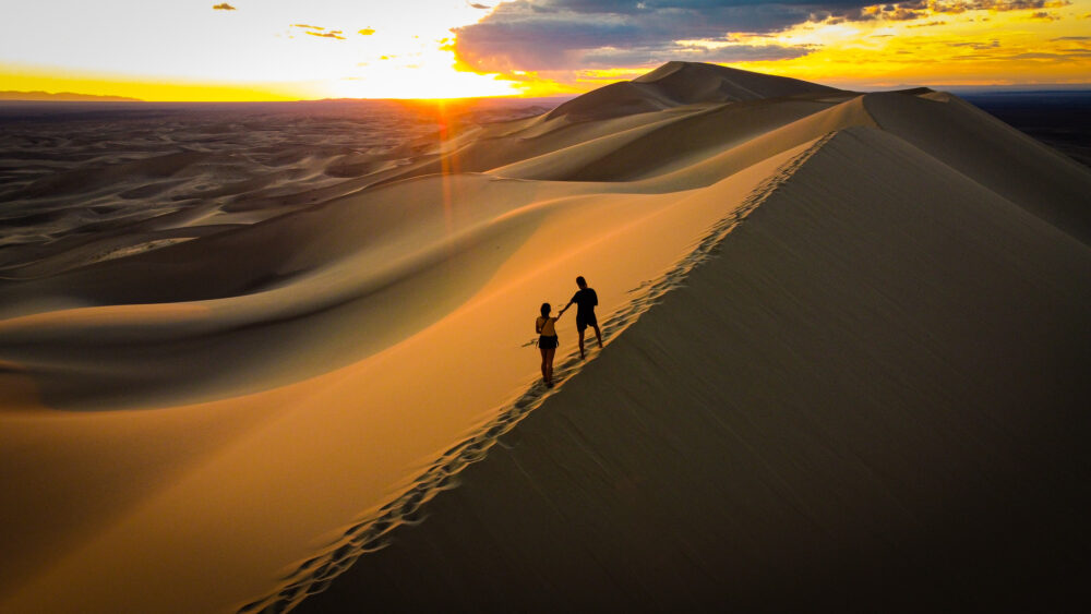 a couple standing on the top of a big dune in Mongolia 