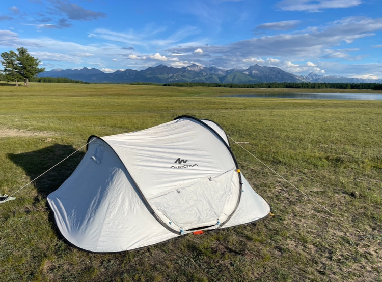 Our tent in a green field with mountains in the background. 