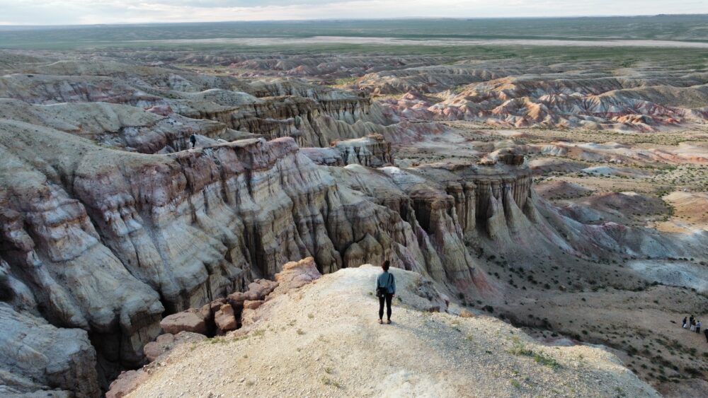 woman standing on the edge of a colorful canyon