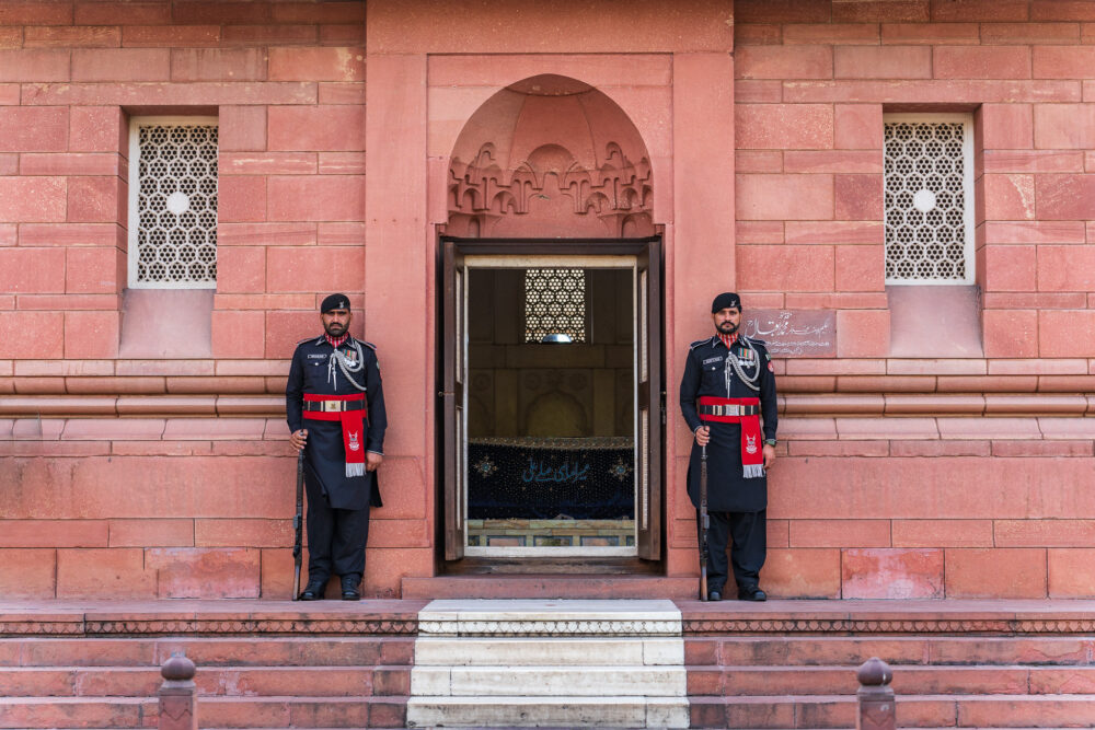 two well-suited guards standing in front of an old red building 